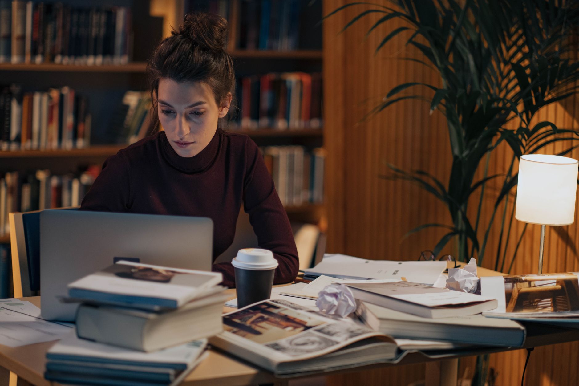 Person working at a desk with books, laptop, and coffee