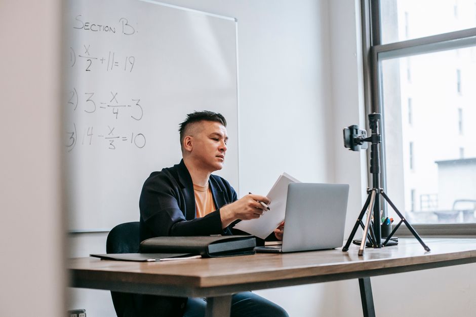 Person taking an online course with a laptop and camera setup
