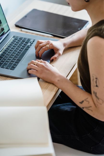 Person taking notes while working remotely on a laptop