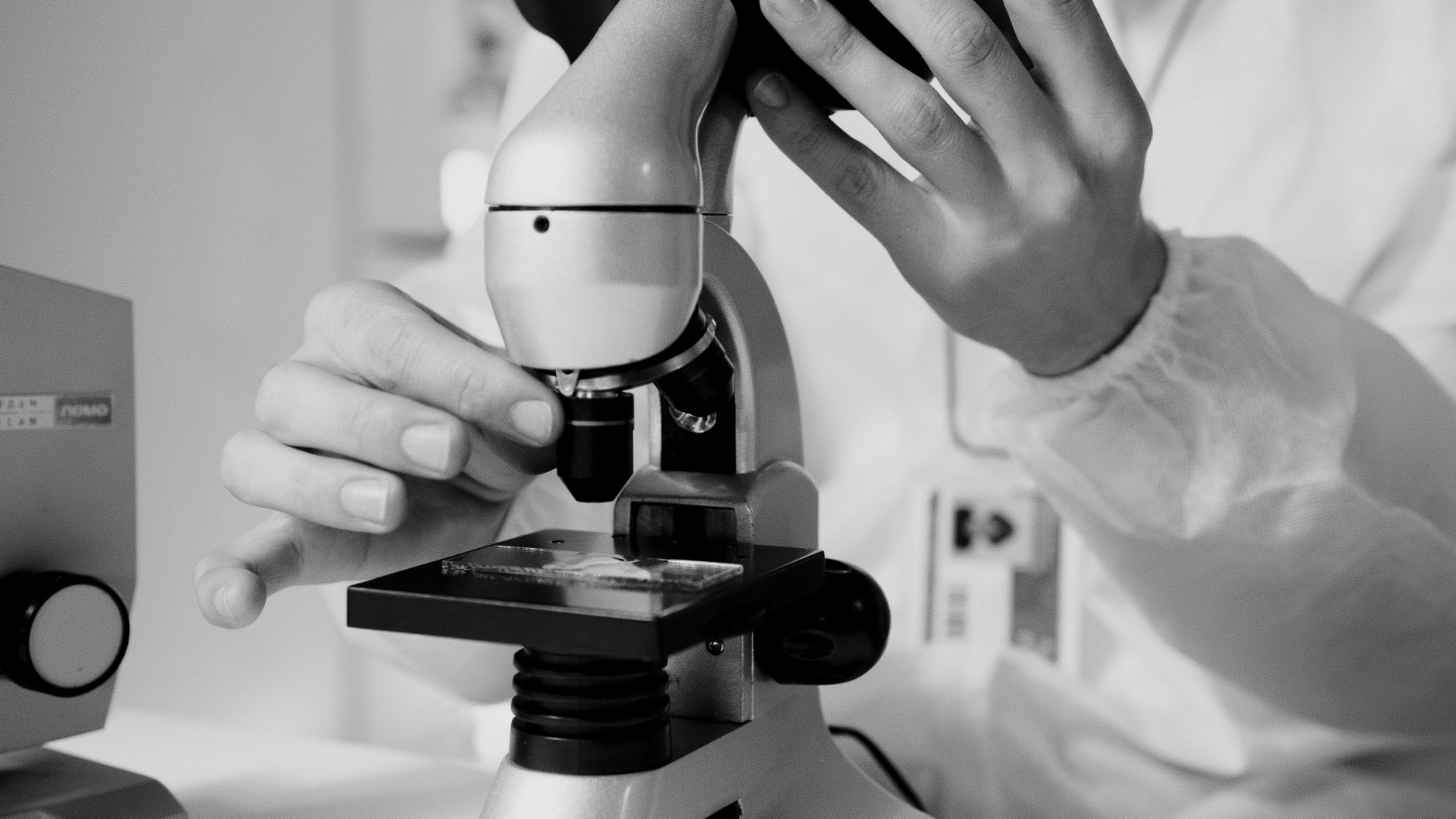 Scientist in a lab coat using a microscope