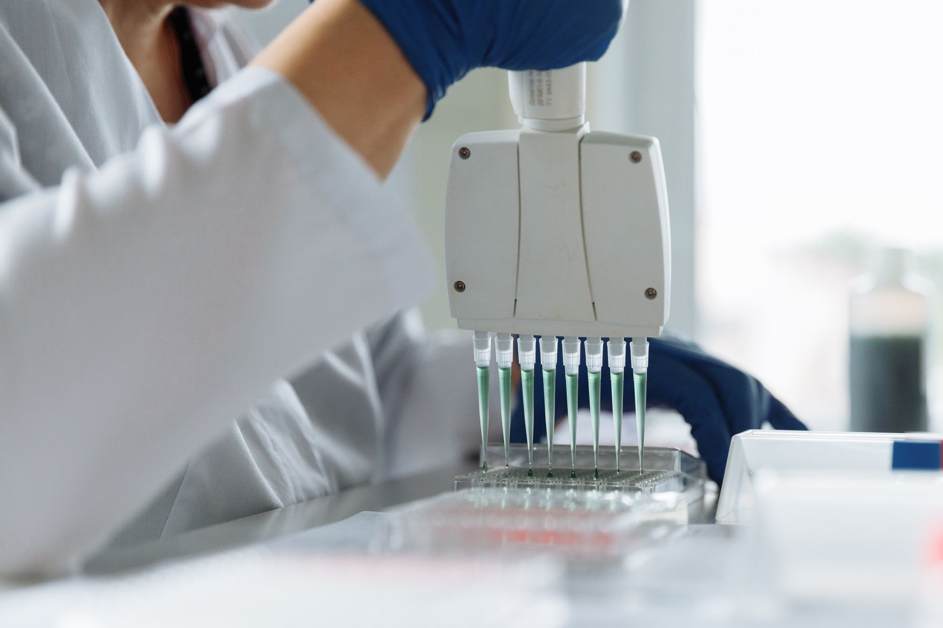 Scientist in a lab coat using a multichannel pipette