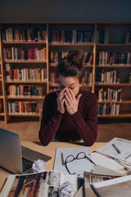 Student studying with books and a laptop in a library