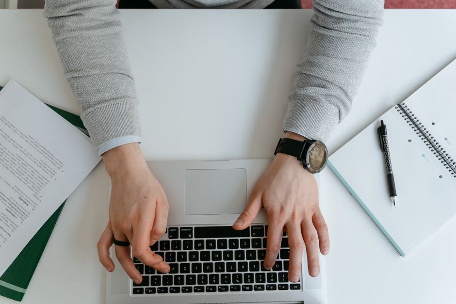 Person typing on a laptop surrounded by documents