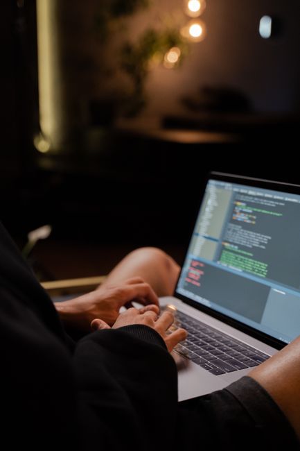Hands typing Python code on a laptop