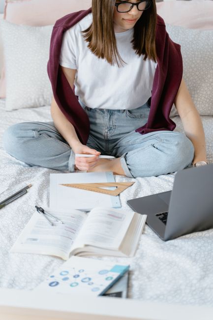 Woman studying online with a laptop and books